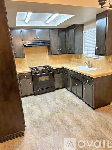 A kitchen with black cabinets and a stove top oven.