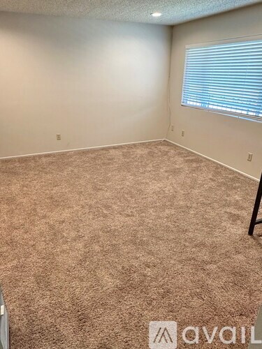 A room with a carpeted floor and a window with blinds.