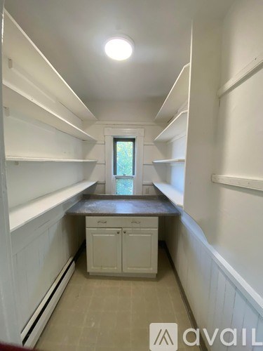 A kitchen area with white cabinets and a window.