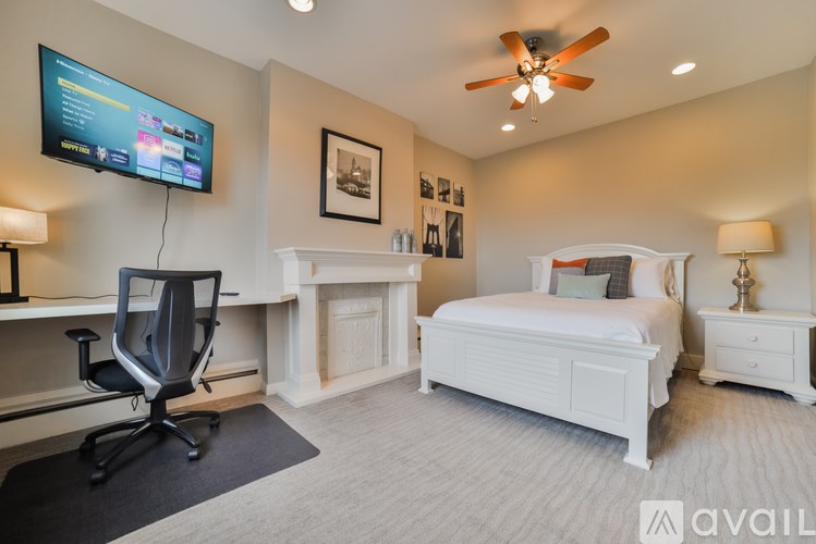 A bedroom with a bed, desk, chair, and television.