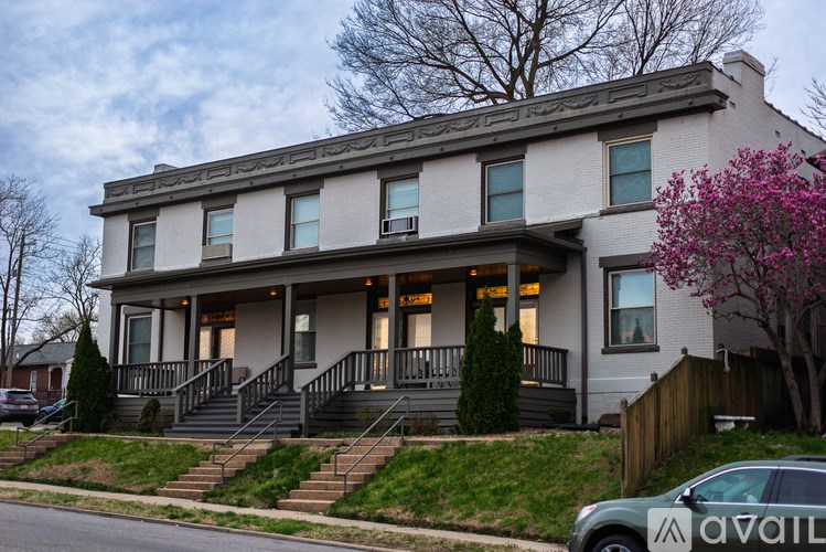 A two-story house with a front porch and a tree with pink flowers.