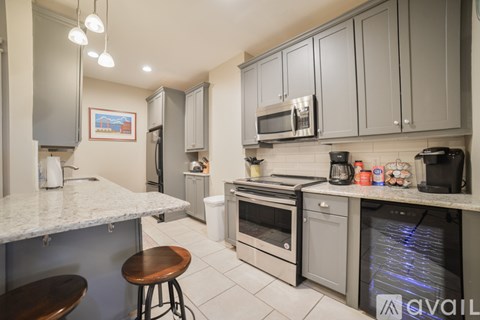 A kitchen with a white counter top and grey cabinets.
