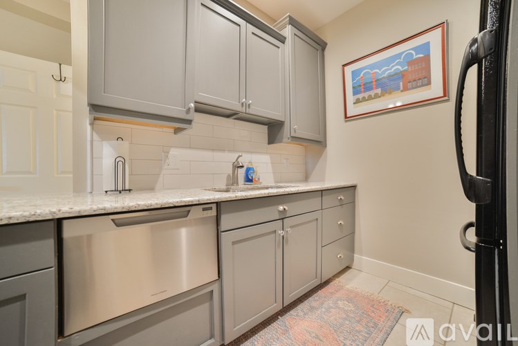 A kitchen with a stainless steel dishwasher and a fridge.