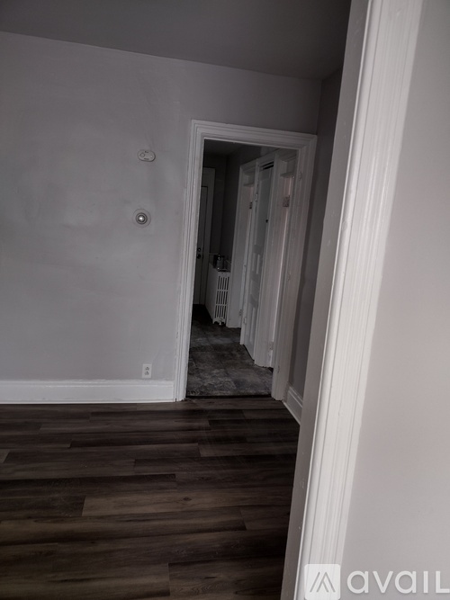 A room with wooden floors and a doorway leading to another room.