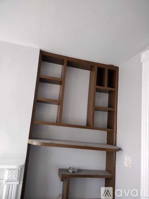 A wooden shelf with glass panes is mounted on a white wall.