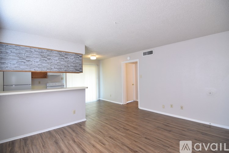 A spacious room with wooden flooring and a stone ledge on the wall.