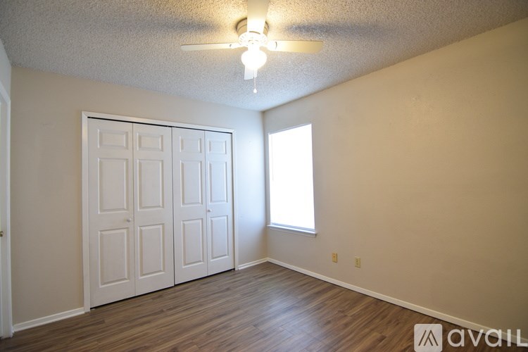 A room with a white door, a window, and a ceiling fan.