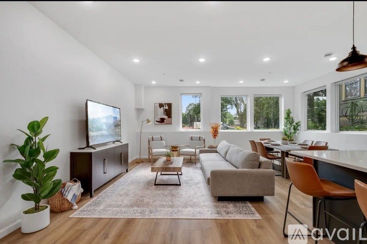 A living room with a flat screen TV, a couch, a coffee table, and a potted plant.