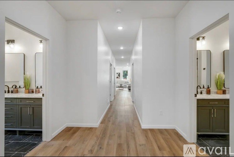 A long, narrow hallway with wooden floors and white walls.