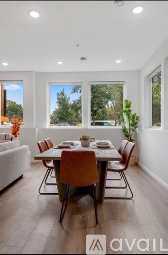 A dining room with a table set for four and a couch in the background.