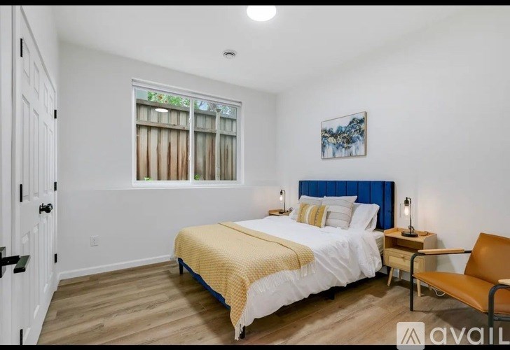 A bedroom with a bed, a chair, and a painting on the wall.