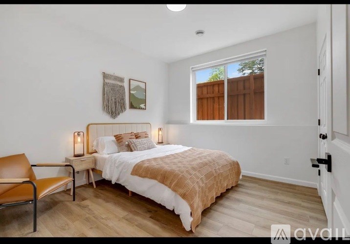 A bedroom with a bed, chair, and two pictures on the wall.