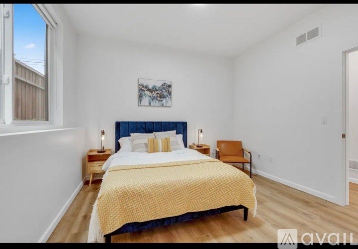 A bedroom with a bed, a chair, and a painting on the wall.