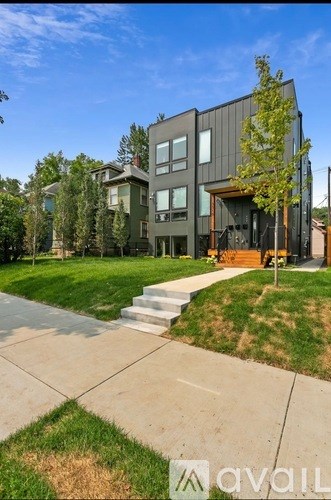 A modern house with a large front yard and a clear blue sky.