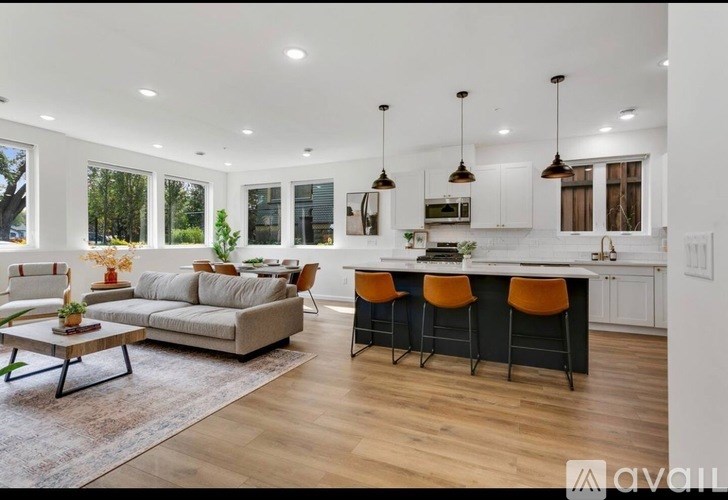 A modern living room with a kitchen area in the background.