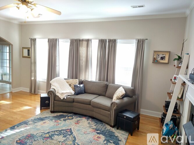 A living room with a grey couch and a chandelier.