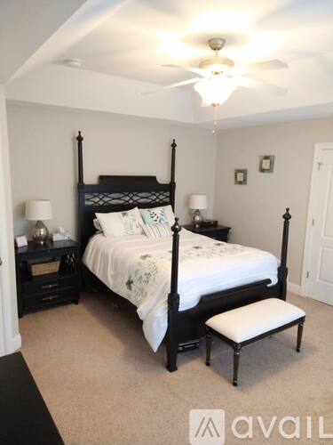 A bedroom with a four poster bed and a white bedspread.