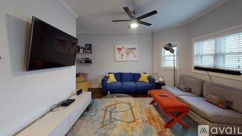 A living room with a blue couch and a television on the wall.