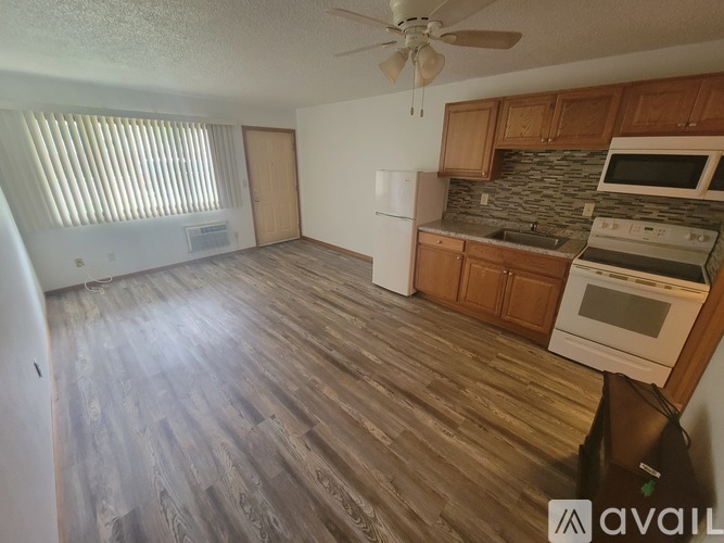 A living room with a carpeted floor and a white refrigerator.