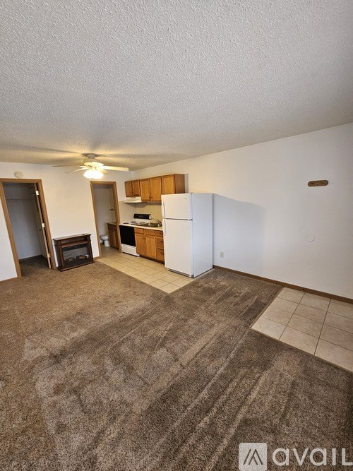 A living room with a carpeted floor and a white refrigerator.