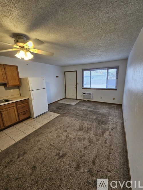 A room with a carpeted floor and a ceiling fan.