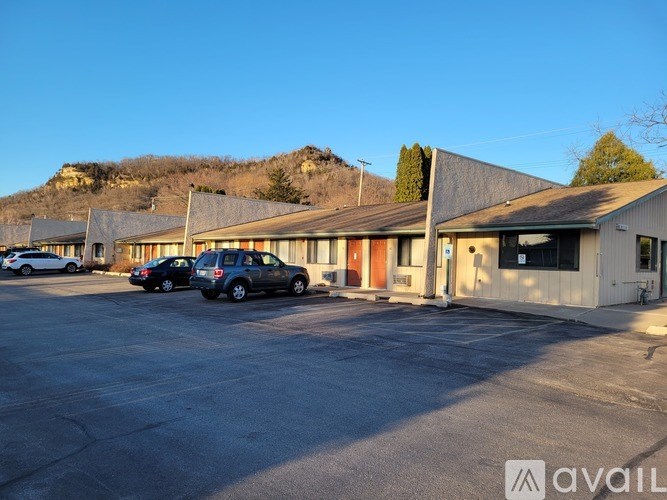 A parking lot with cars and a building with a mountain in the background.