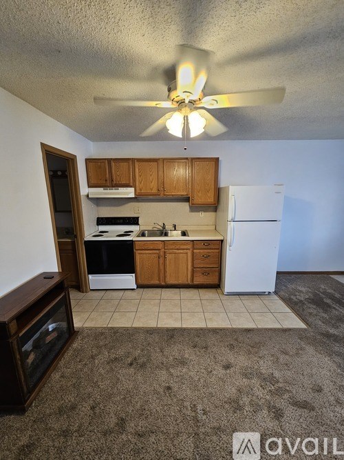 A kitchen with a white refrigerator, white oven, and brown cabinets.