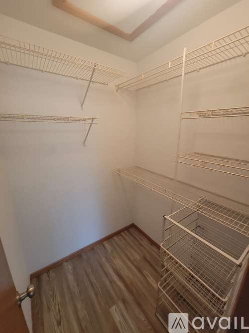 A room with a ceiling fan and a kitchen area with a refrigerator.