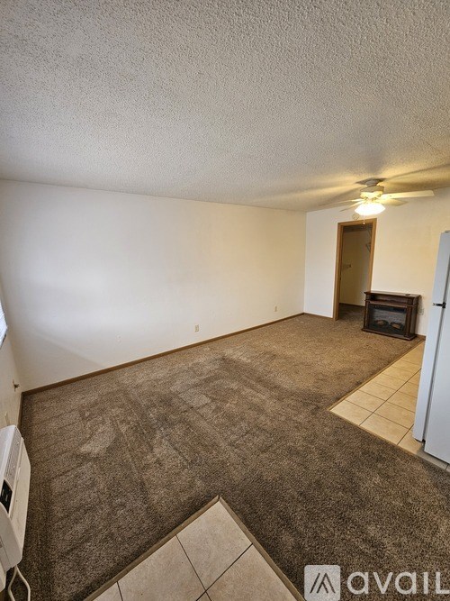 A room with a carpeted floor and a door in the background.