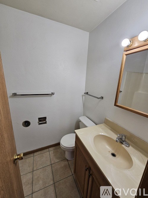 A bathroom with a toilet, sink, and mirror.