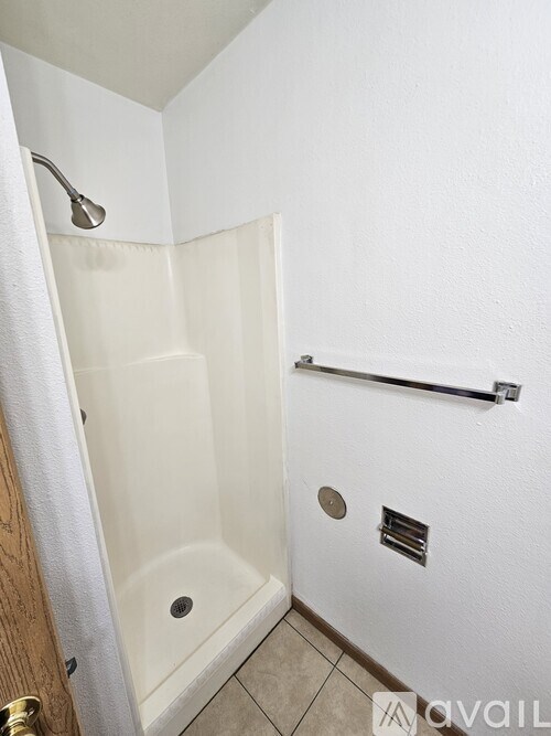 A white bathroom with a shower and a towel hanging on the door.