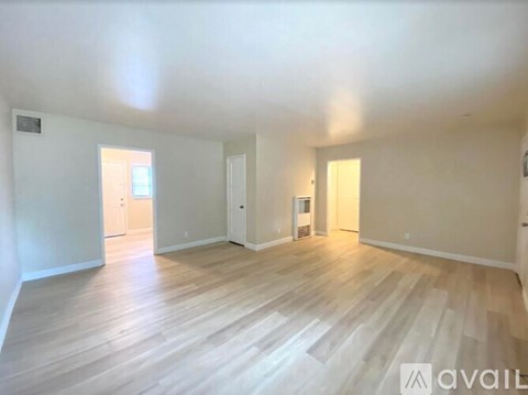 A spacious room with wooden flooring and white walls.