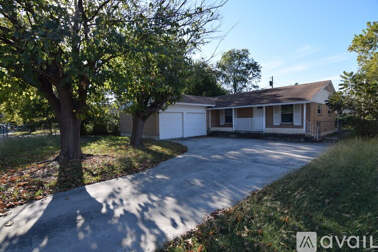 A house with a driveway and a tree in front.