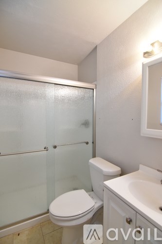 A small bathroom with a toilet, sink and shower.