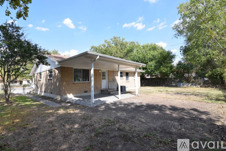 A house with a brown exterior is surrounded by trees and has a dirt area in front.