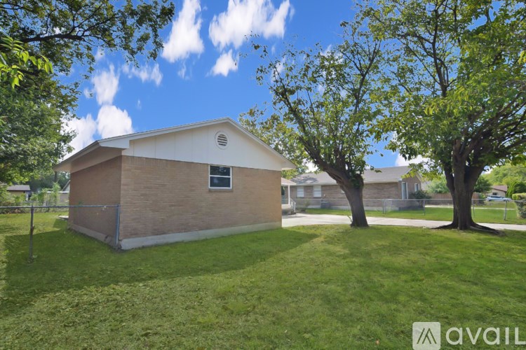 A small house with a white roof is surrounded by trees and grass.