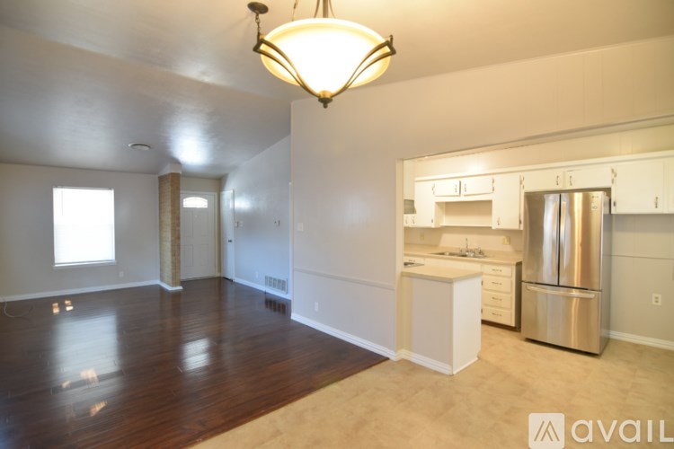 A kitchen area with a refrigerator, sink, and cabinets.