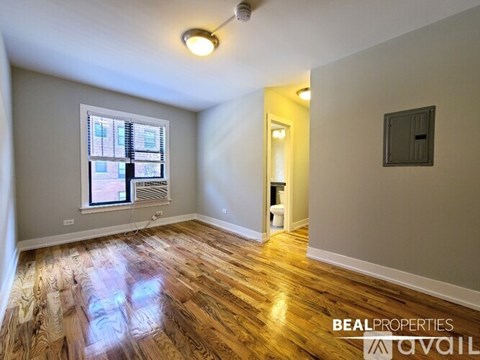 A room with wooden flooring and a window with blinds.