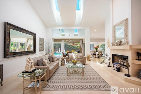 A living room with a glass coffee table and a fireplace.