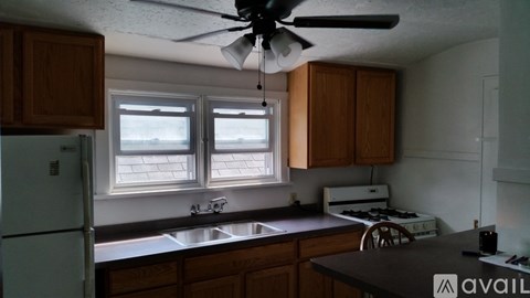 A kitchen with wooden cabinets and a white ceiling fan.