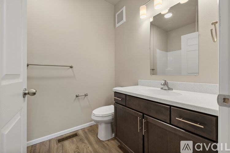 A bathroom with a toilet, sink, and mirror.