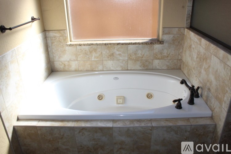 A bathroom with a white tub and a window with a frosted glass.