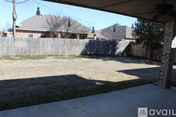 A backyard with a wooden fence and a house in the background.
