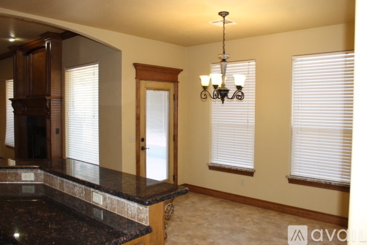 A kitchen with a granite counter top and a chandelier hanging from the ceiling.