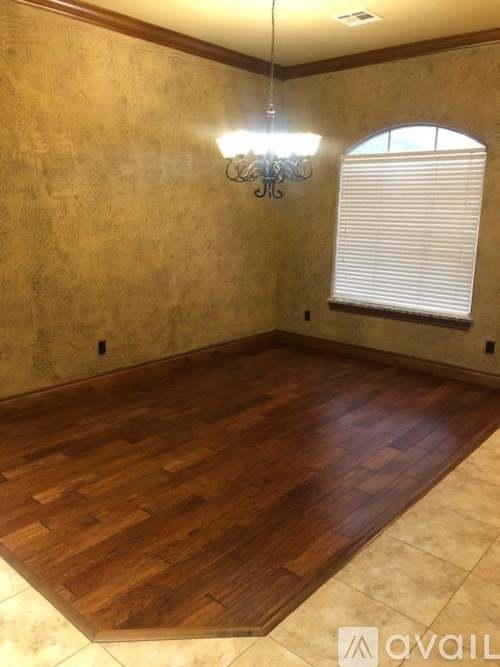 A room with wooden flooring and a chandelier.