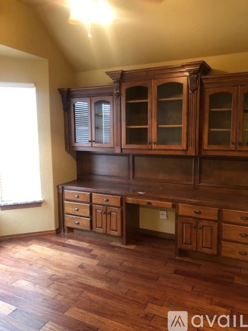 A wooden cabinet with glass doors and drawers is in a room with wooden flooring.
