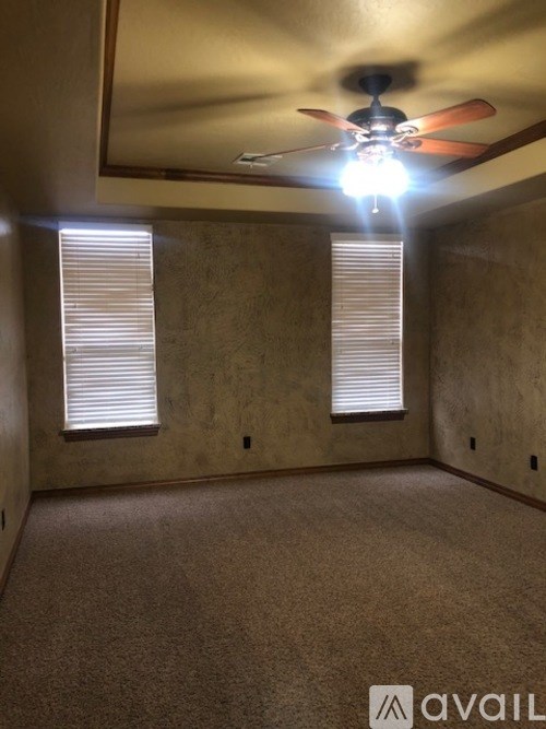 A room with a ceiling fan and two windows.