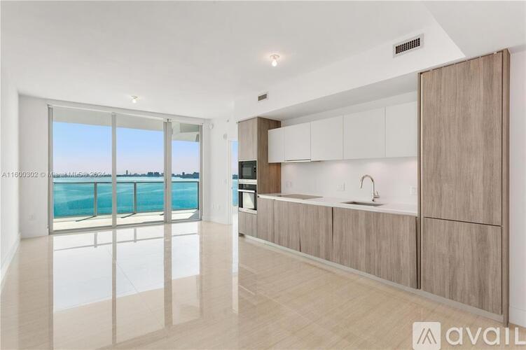 A modern kitchen with a view of the pool and sky.