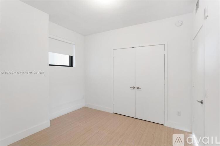 A white bedroom with a door and a window.