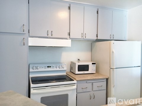 A kitchen with white cabinets and appliances including a microwave, oven, and refrigerator.